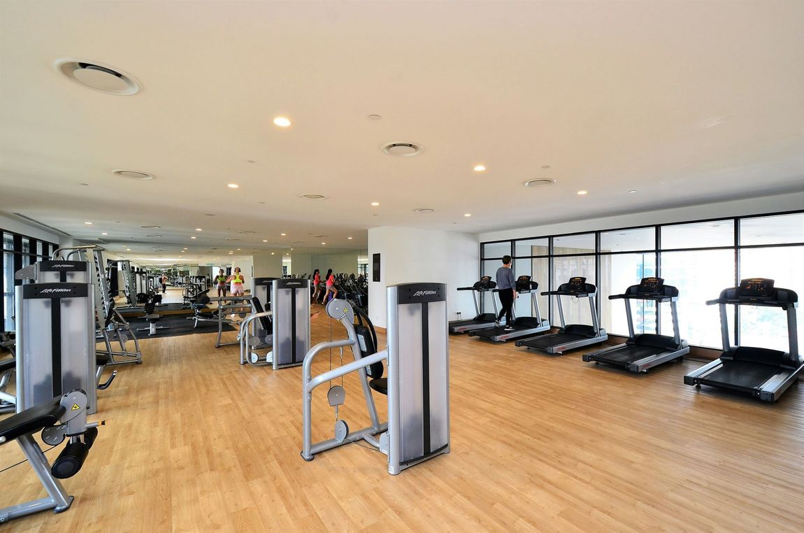 Spacious modern gym with treadmills, weight machines, and wood flooring