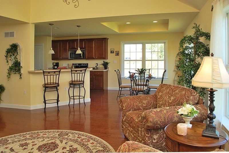 A living room with two chairs and a lamp and a kitchen in the background