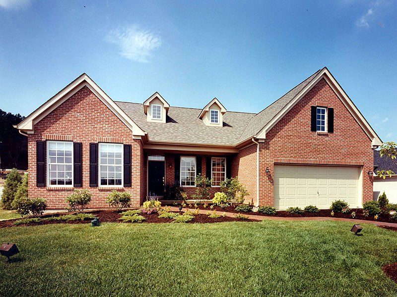 A brick house with a white garage door and black shutters