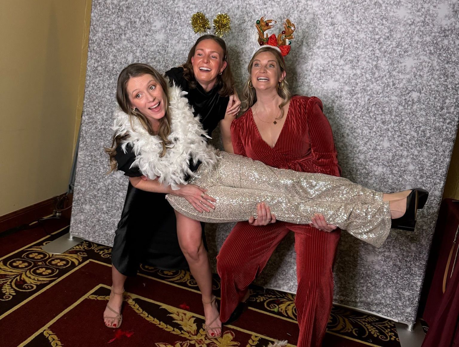 Three women are posing for a picture in front of a photo booth.