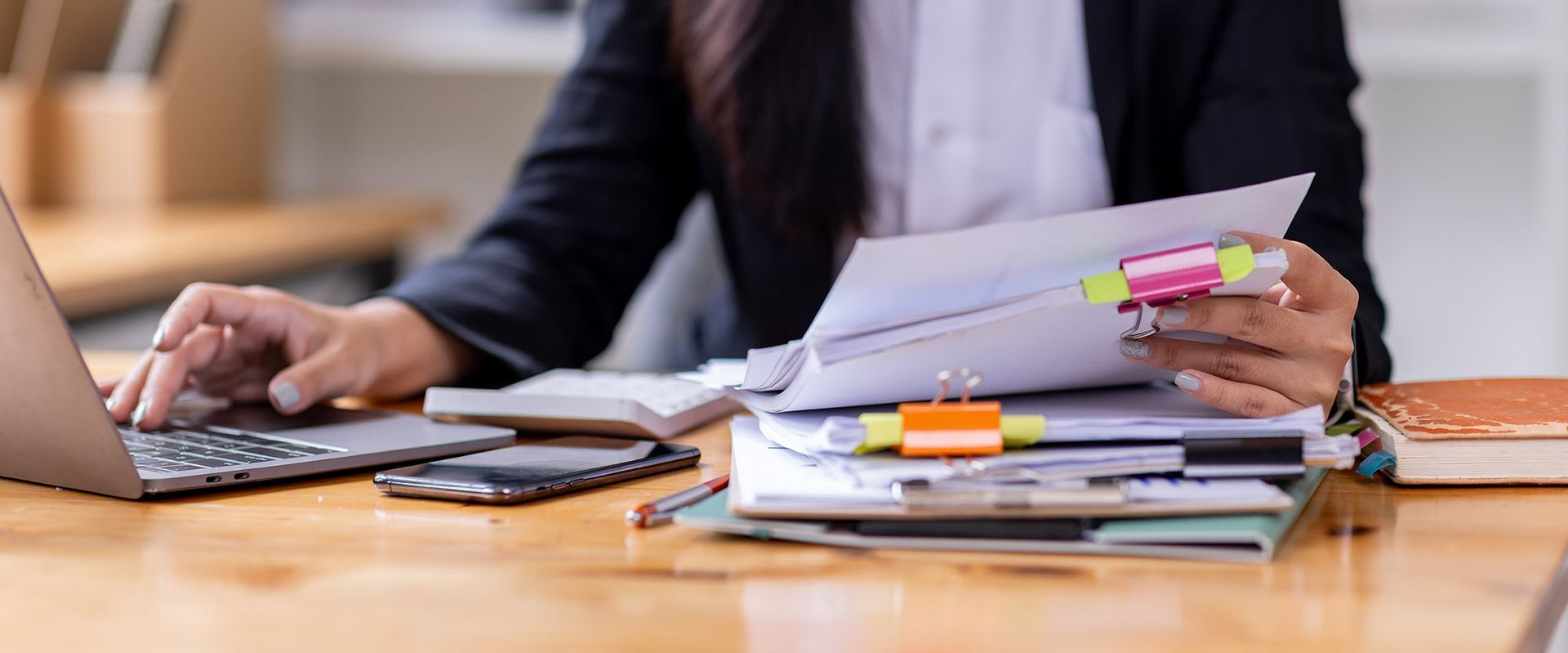 Person working at desk with laptop and documents.