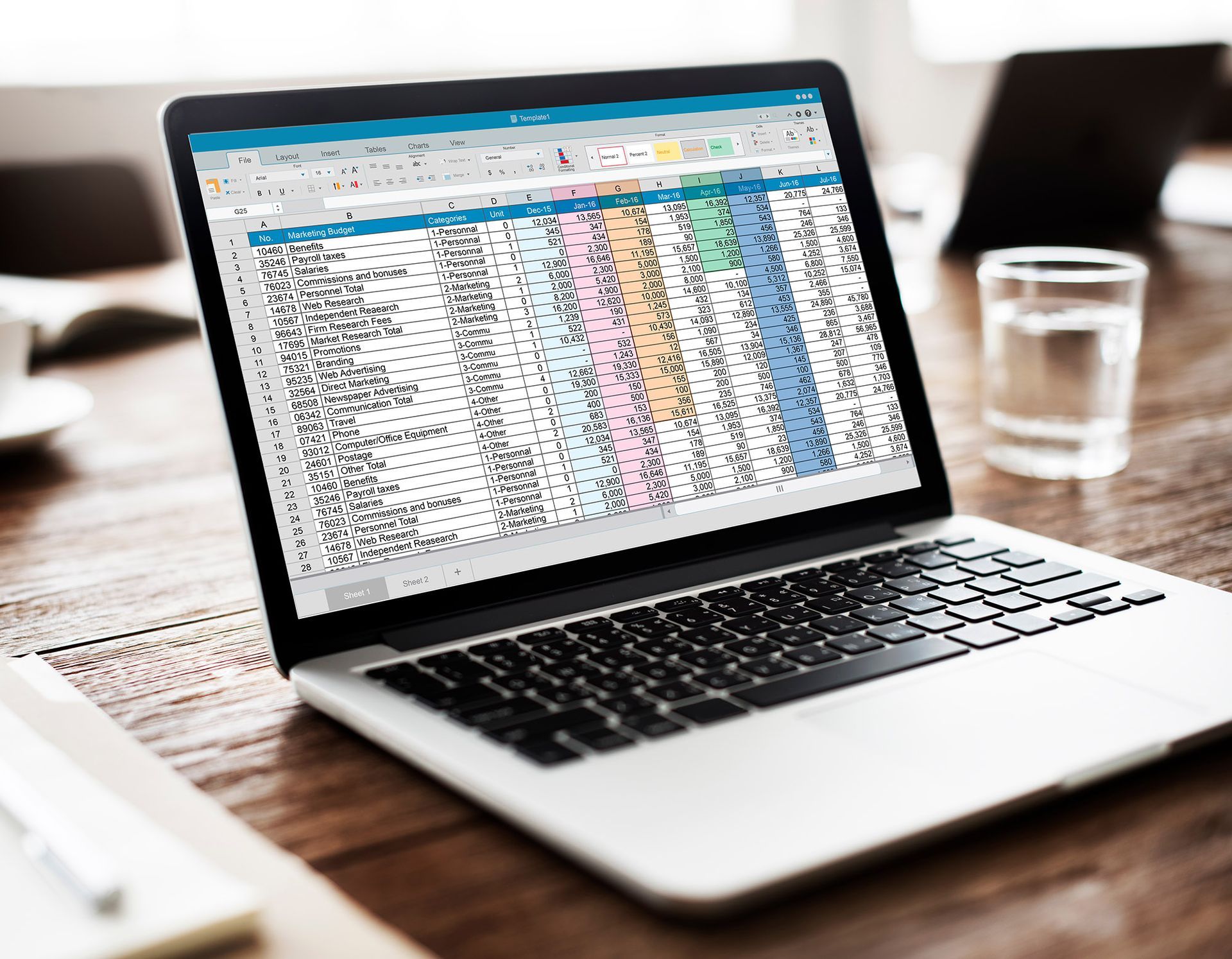 Laptop displaying a colorful spreadsheet on a wooden desk.