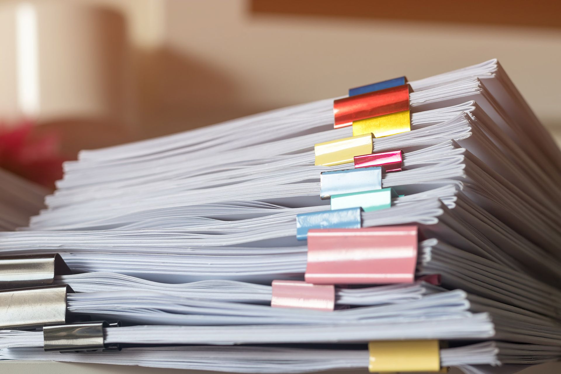 Stack of white papers secured with colorful binder clips.