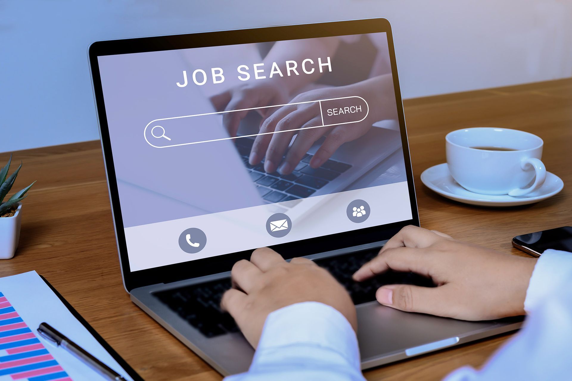 Person using laptop for job search, with screen displaying search bar and coffee cup nearby.