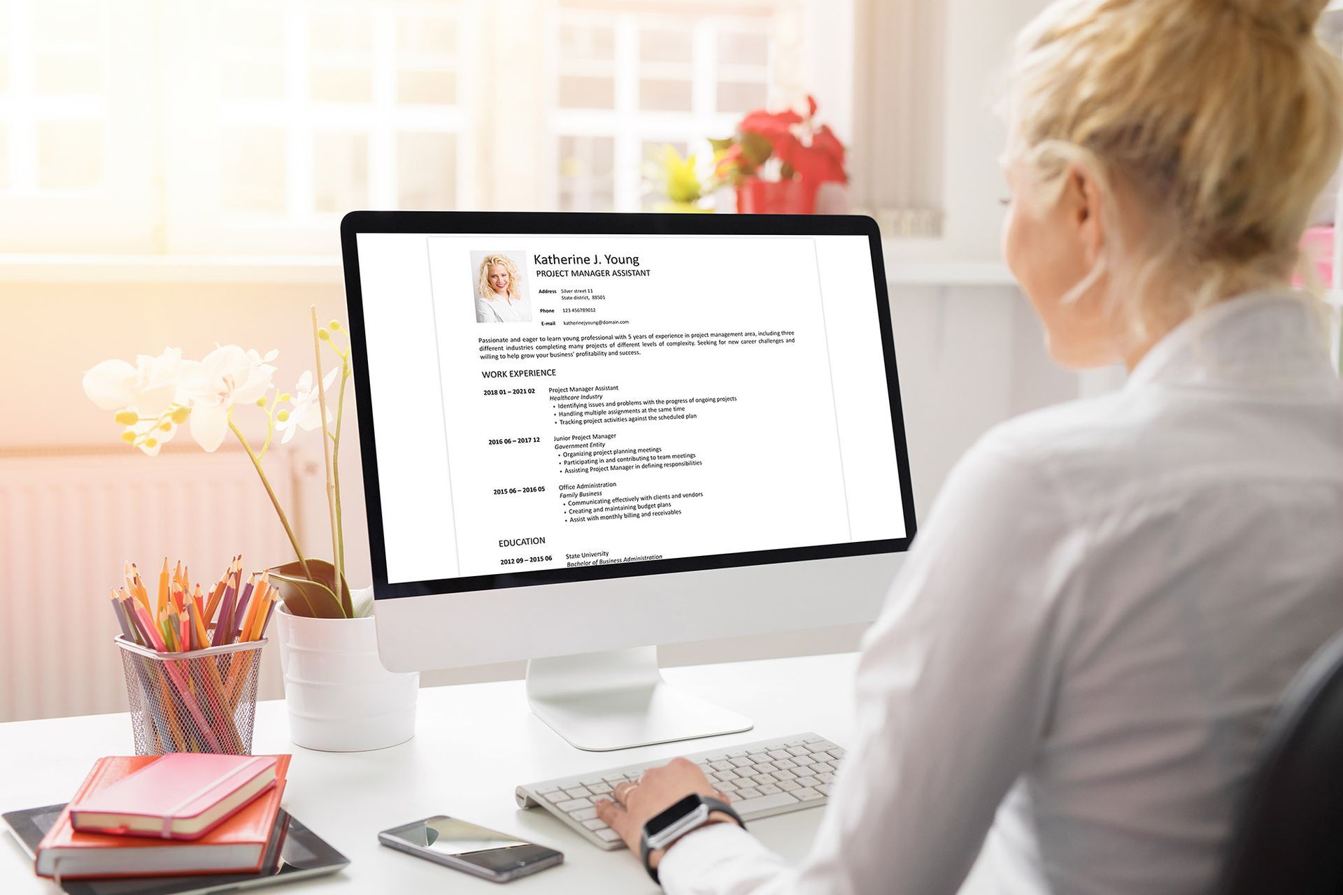 Woman working on a computer at a desk, reviewing a resume.