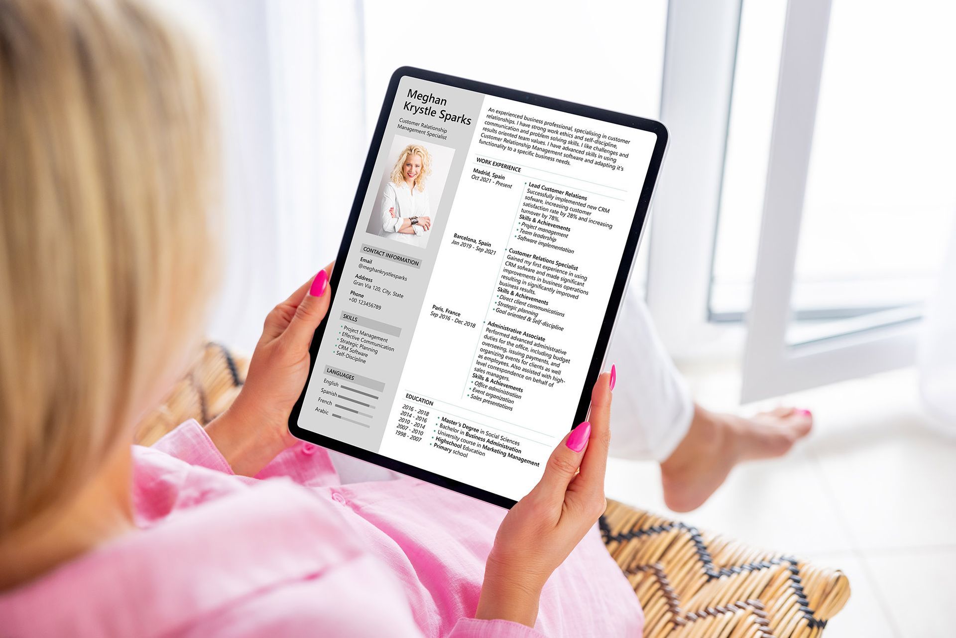 Woman holding a tablet with a resume displayed; light background, interior.