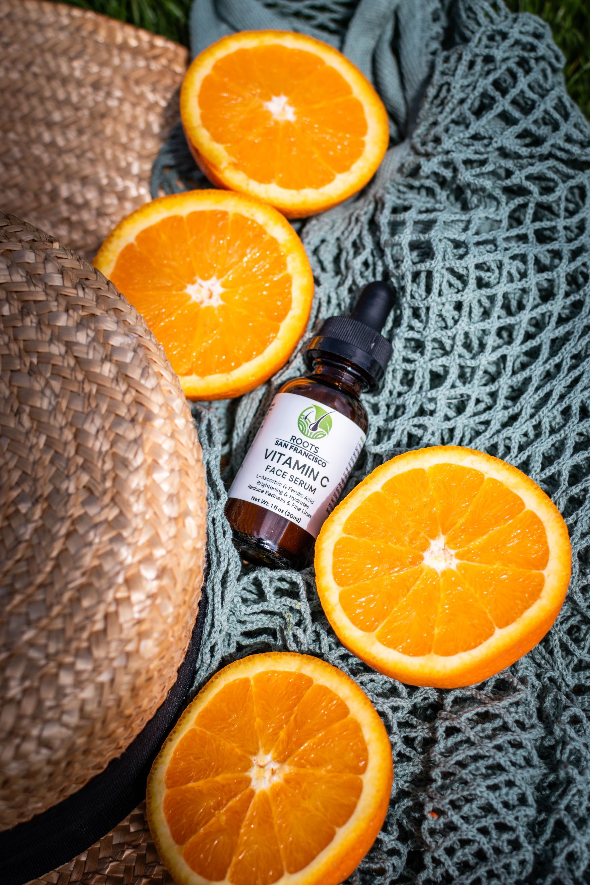 A bottle of vitamin c surrounded by oranges and a straw hat.