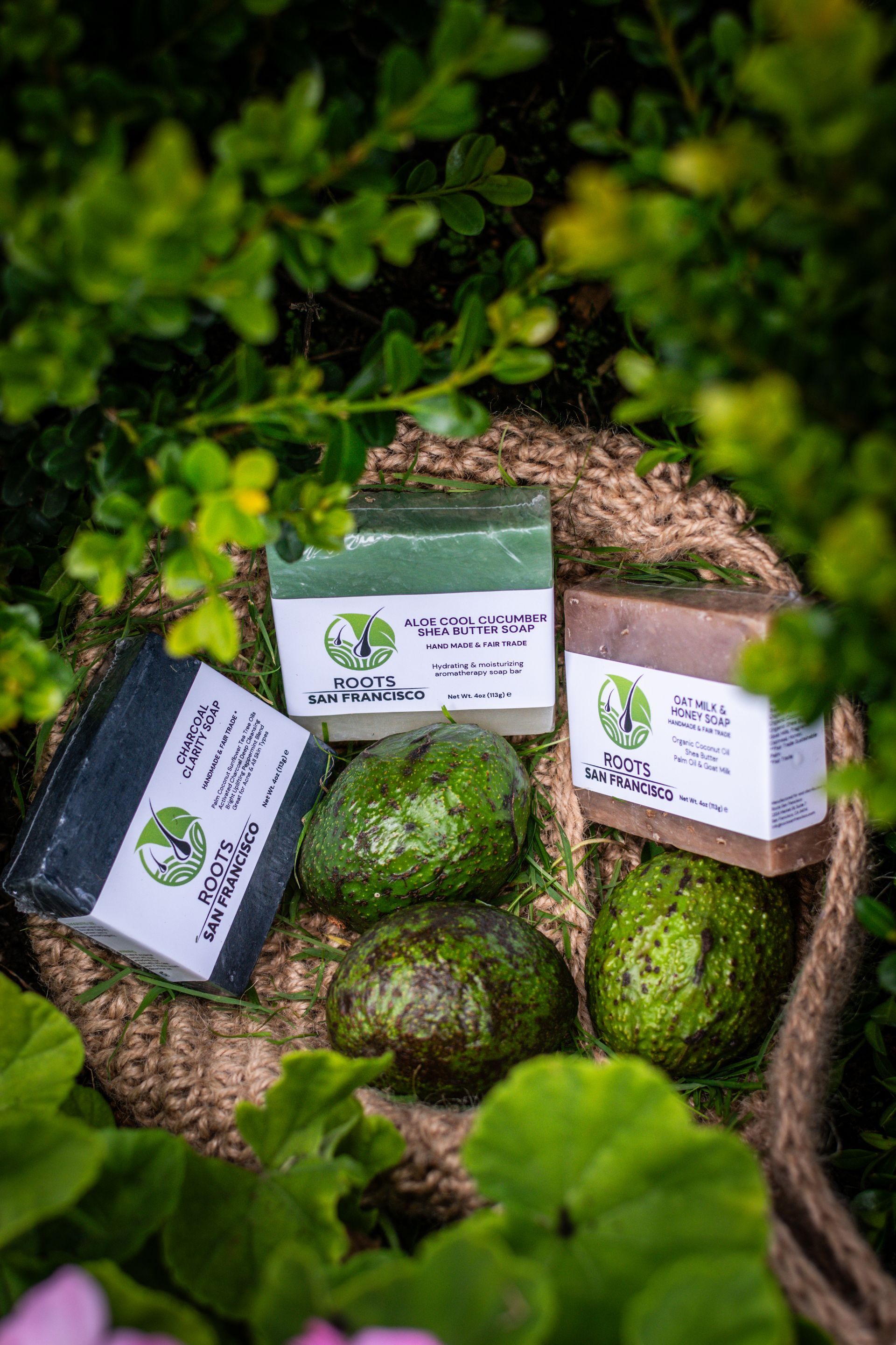 Three soap bars are sitting in a basket with avocados.