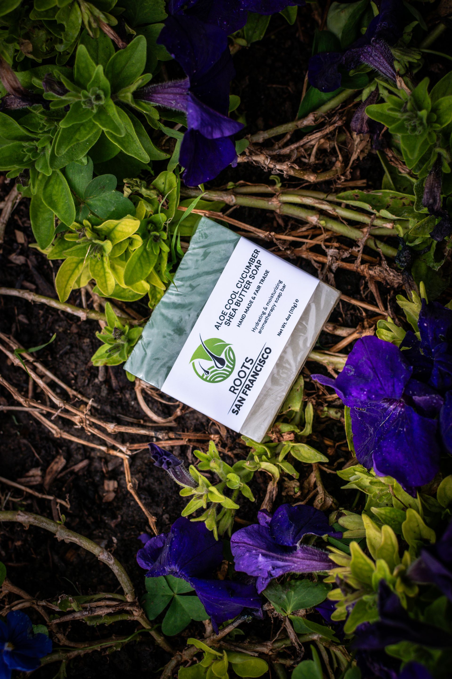 A bar of soap is sitting on top of a pile of purple flowers.