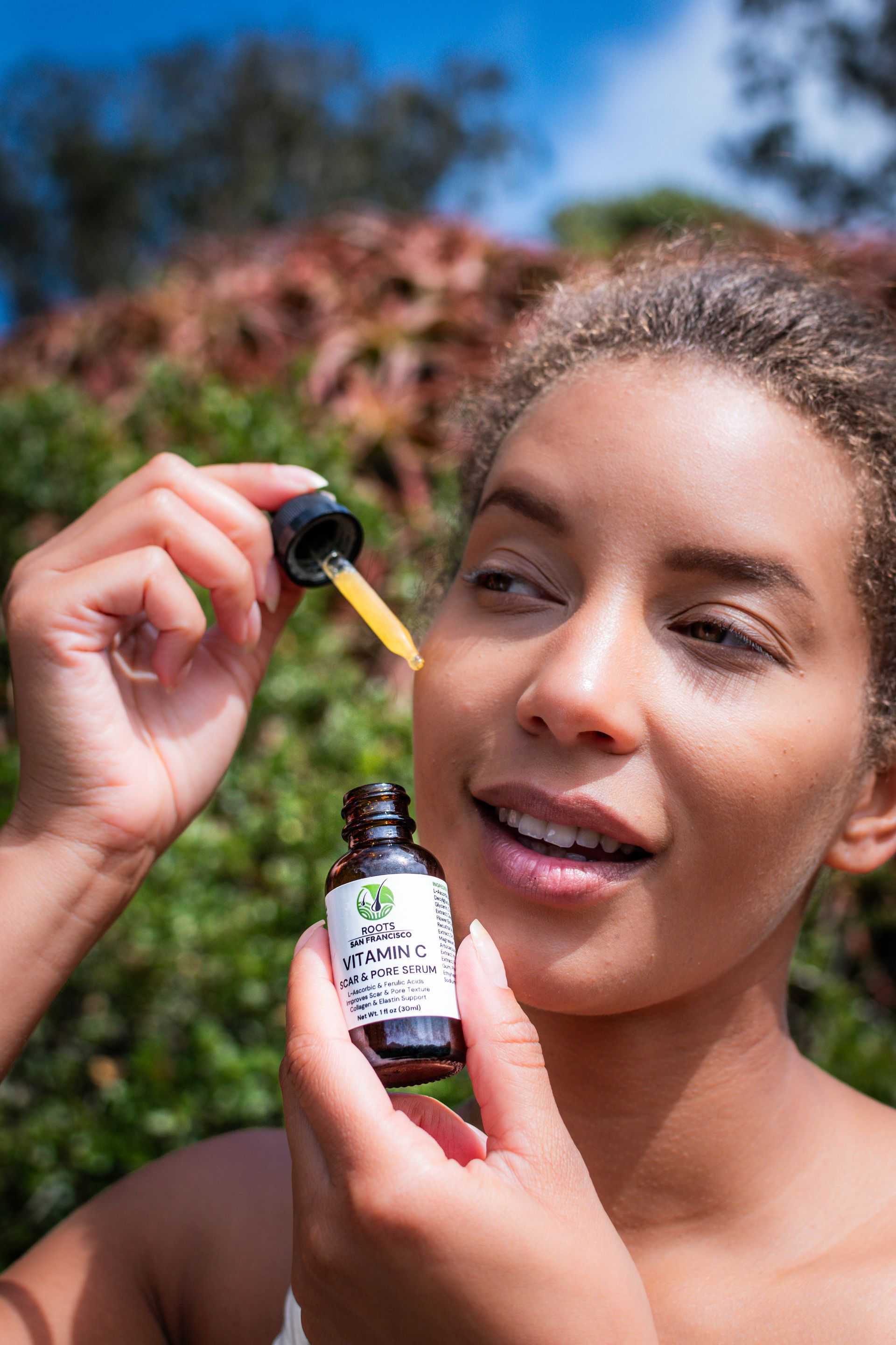 A woman is applying a drop of oil to her face.