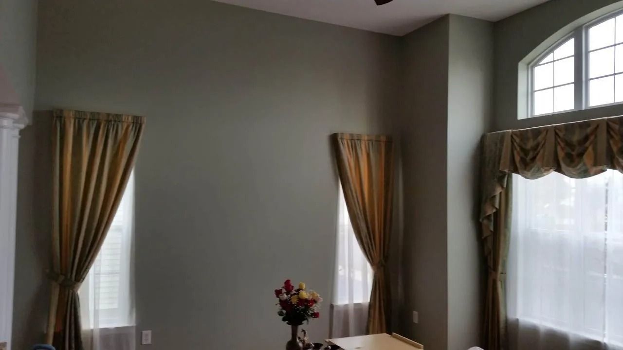 Interior room with tall windows, olive green walls, and gold curtains.