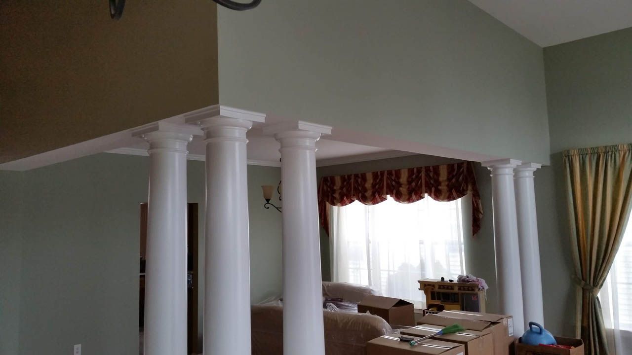 White pillars support a ceiling in a room with light green walls.