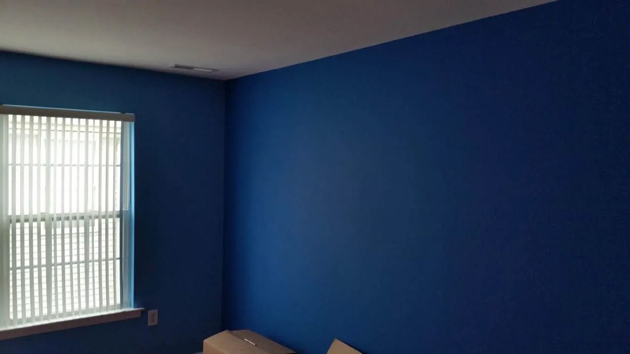 Room interior with a blue painted wall and a window with white blinds.