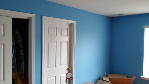 Blue-painted room with white doors and a window, containing some visible objects and boxes.