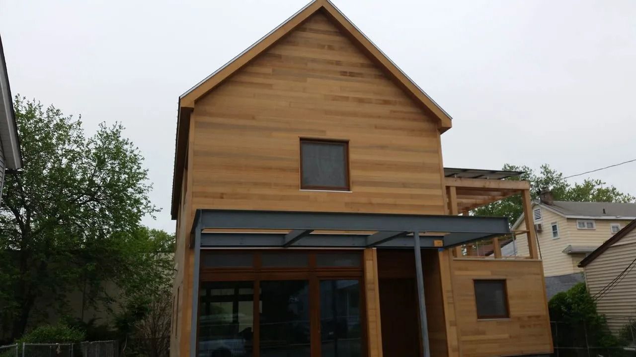 Two-story wooden house under construction with a metal awning.