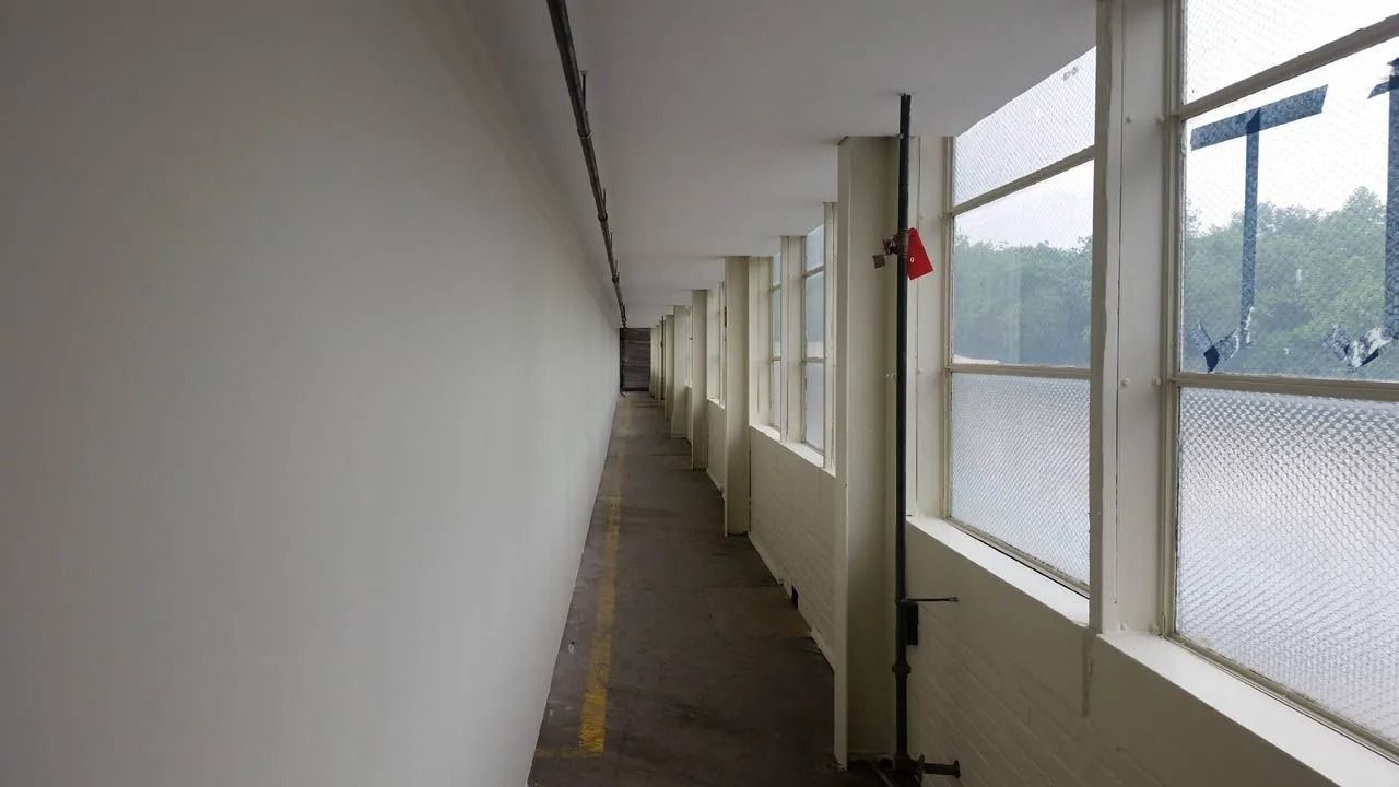 Narrow hallway with windows on one side and a blank wall on the other.
