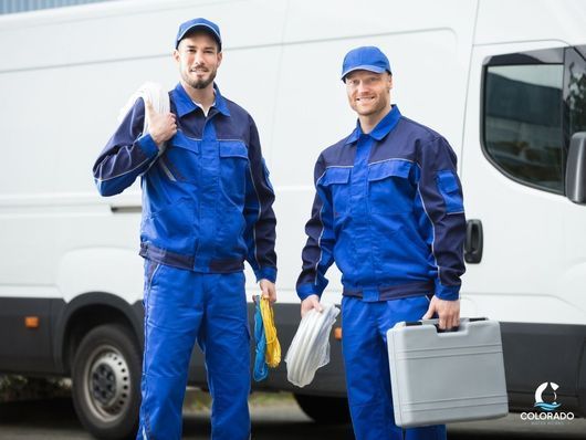 Professional Plumbers in Denver, CO posing for camera in front of their van.