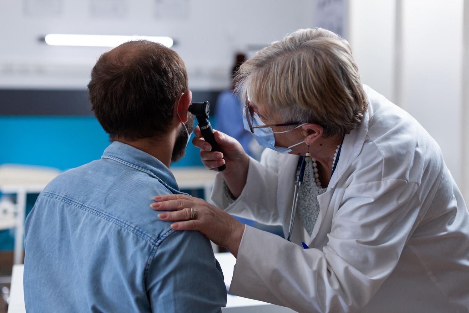 Doctor examining a patient's ear with an otoscope in a medical office.