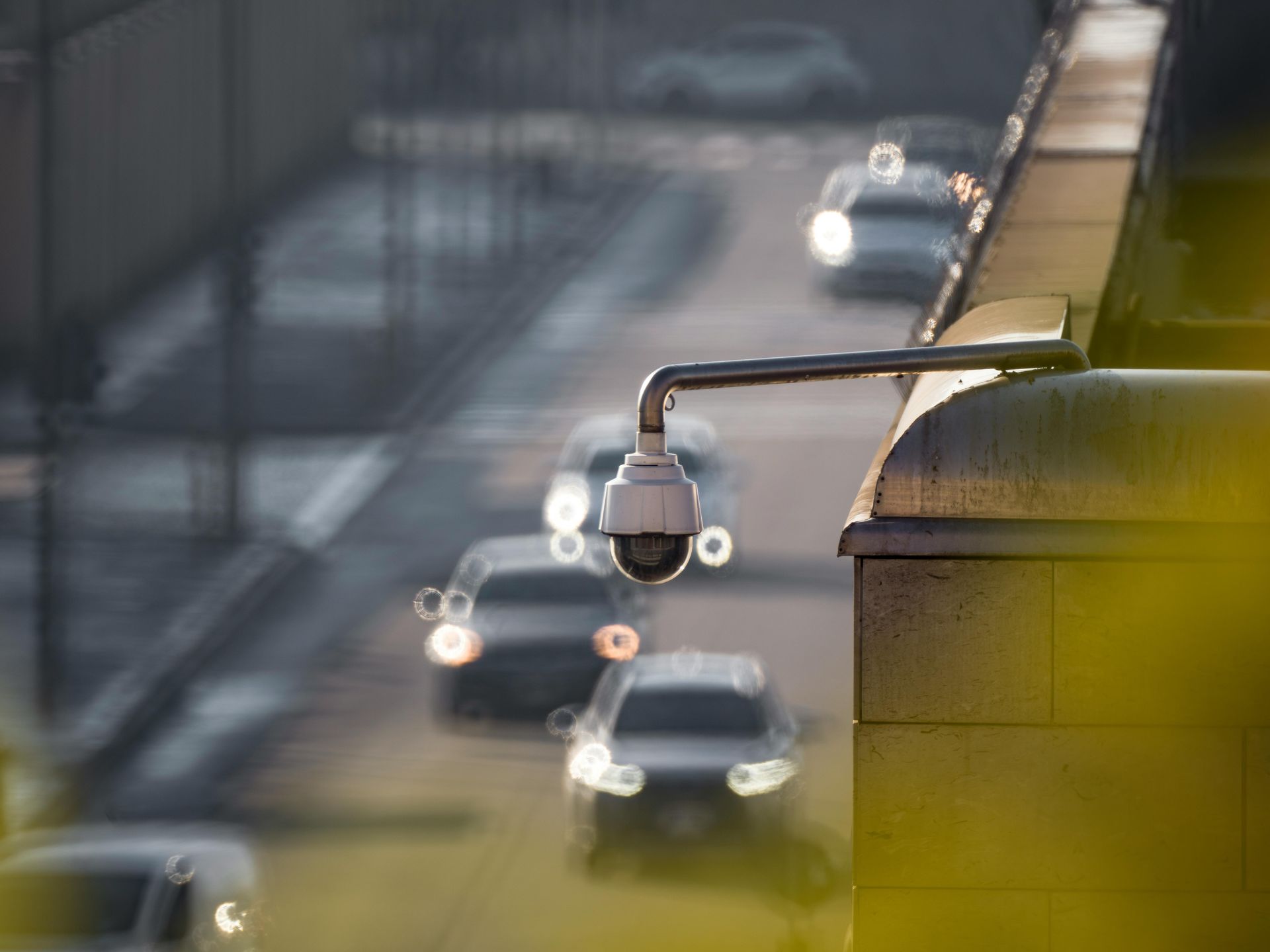 Security camera overlooking a busy city street with cars, golden hour lighting.