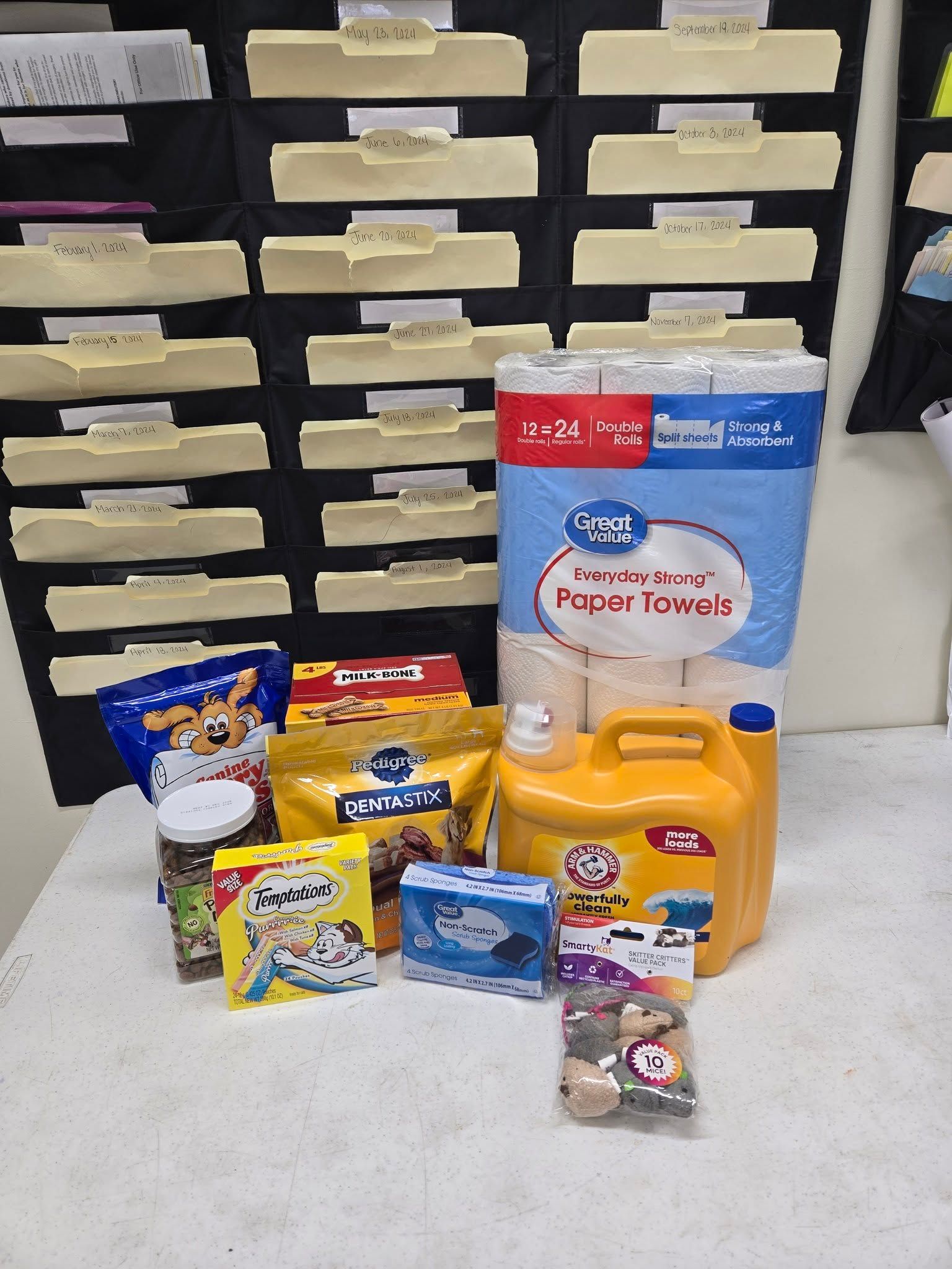 A tan, happy dog sits on a navy blue blanket featuring white elephant patterns, surrounded by toys near colorful bins.