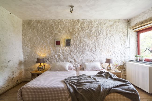 Een slaapkamer met twee bedden en een stenen muur.