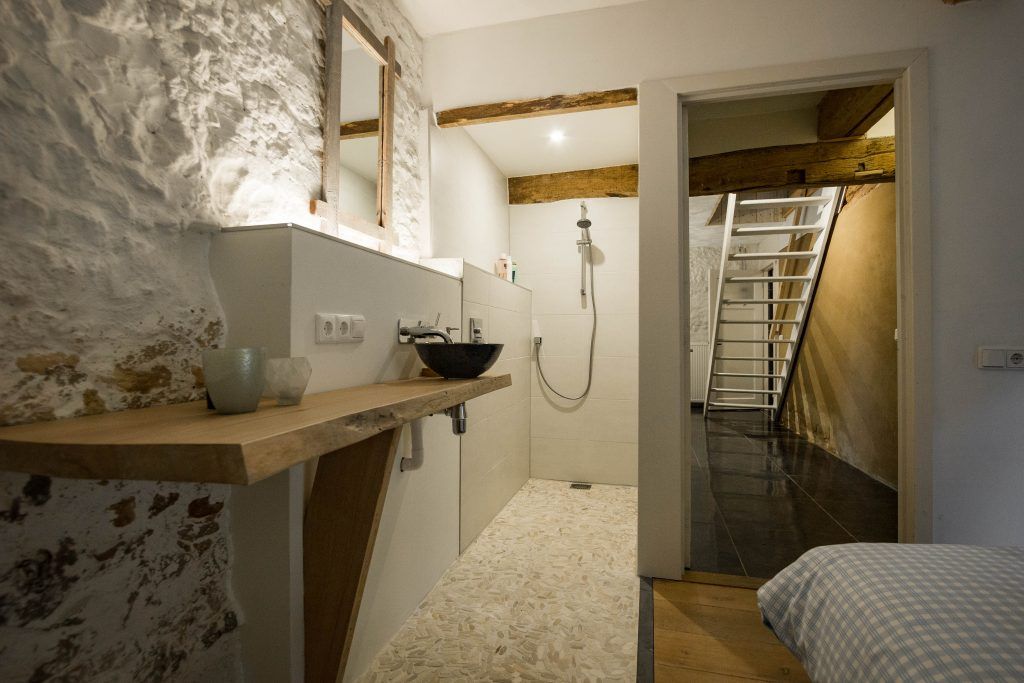 Een badkamer met wastafel, spiegel en douche.