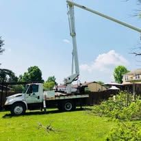 White utility truck with an extended boom in a grassy yard under a blue sky.