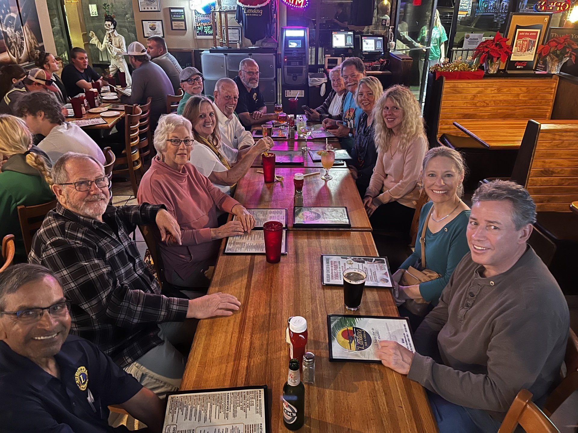 Group of people seated at a long table in a restaurant, smiling and socializing.
