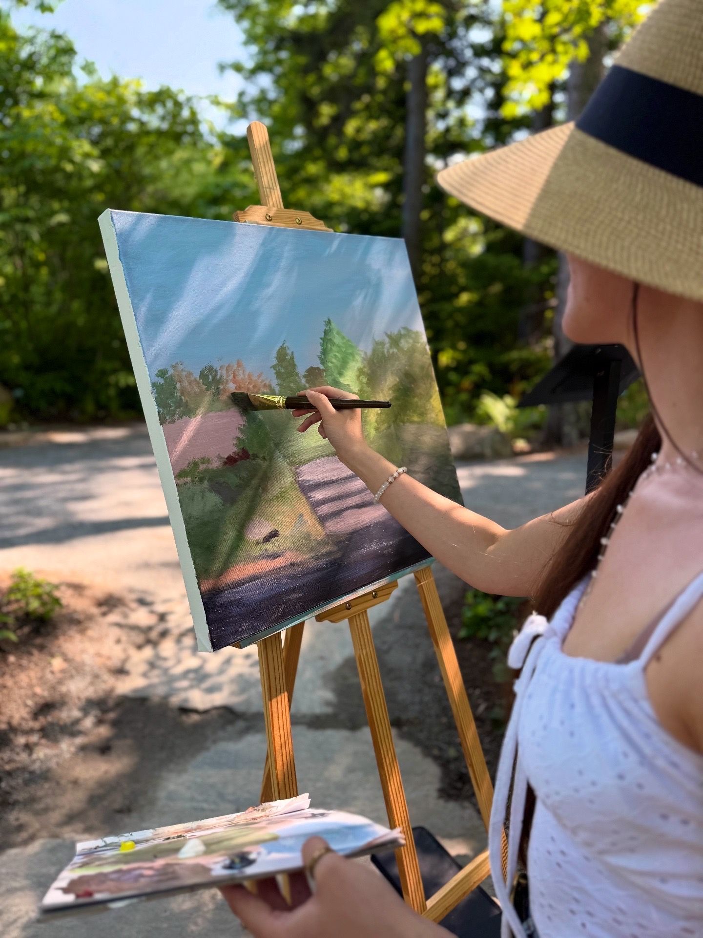 A woman is painting a picture on an easel.