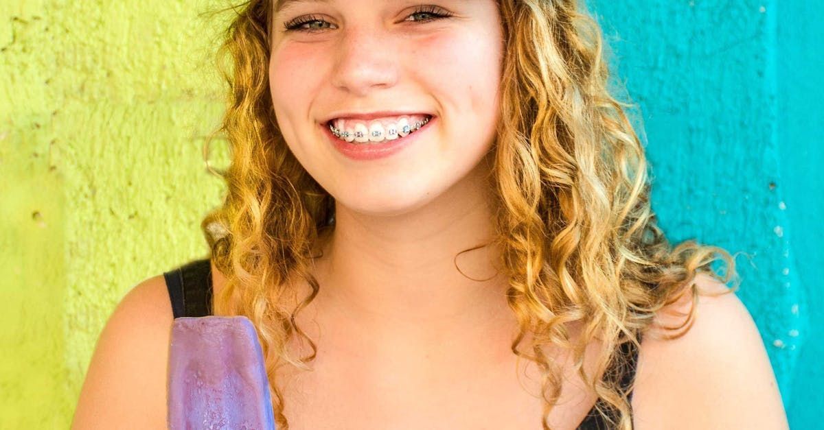 Girl smiling with braces in front of a colorful wall.