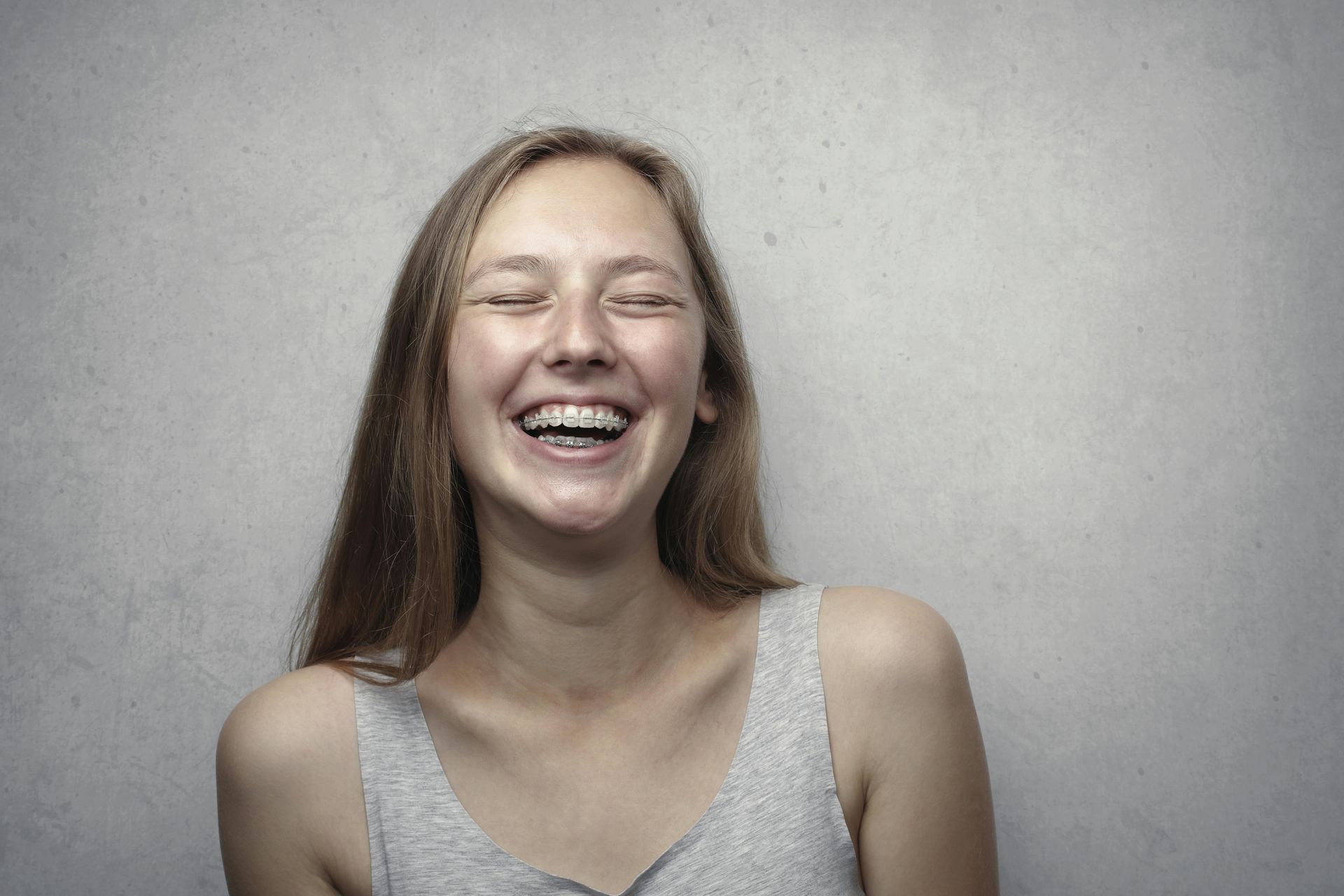 A young woman is laughing with her eyes closed.