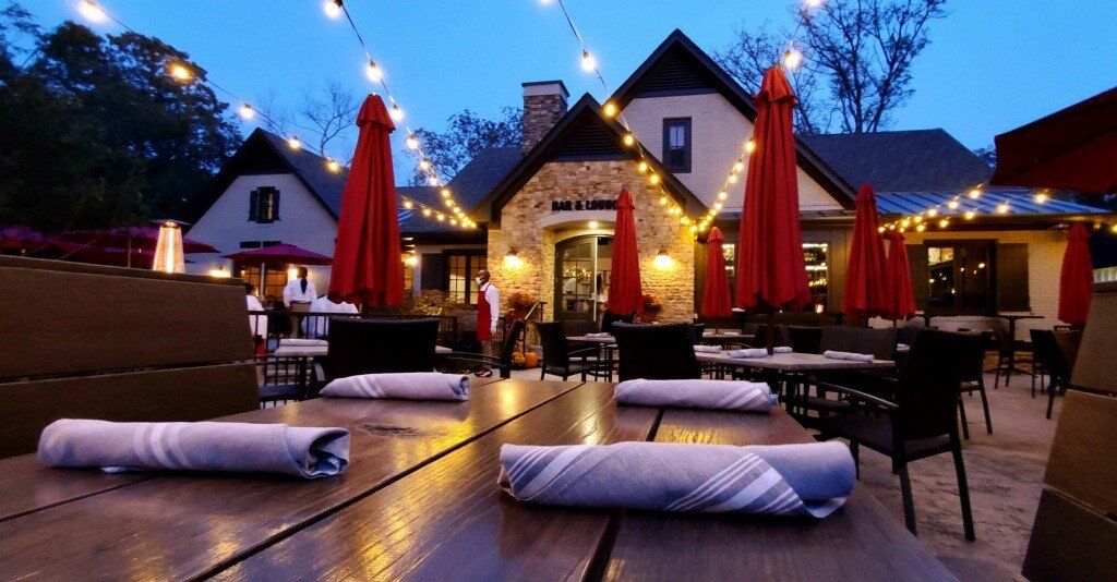 a restaurant with tables and chairs outside at night with red umbrellas and lights .