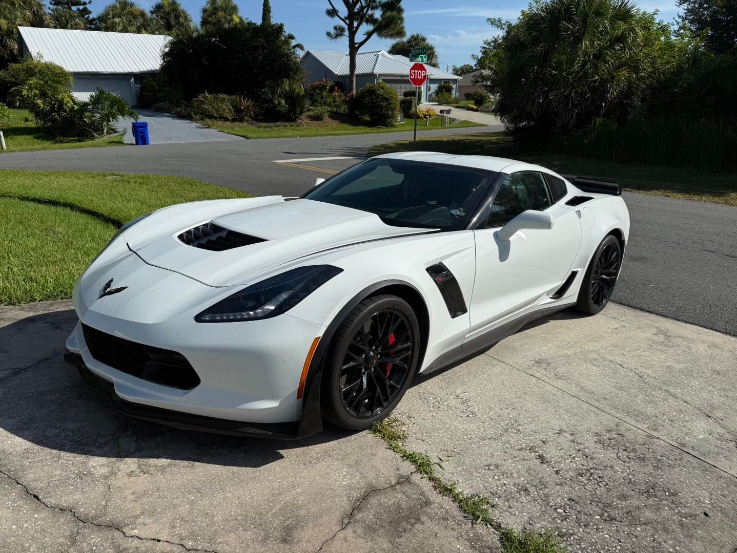White Corvette sports car parked on a driveway in a residential neighborhood.