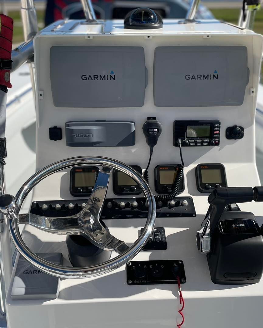 Boat dashboard with Garmin displays, steering wheel, and throttle.