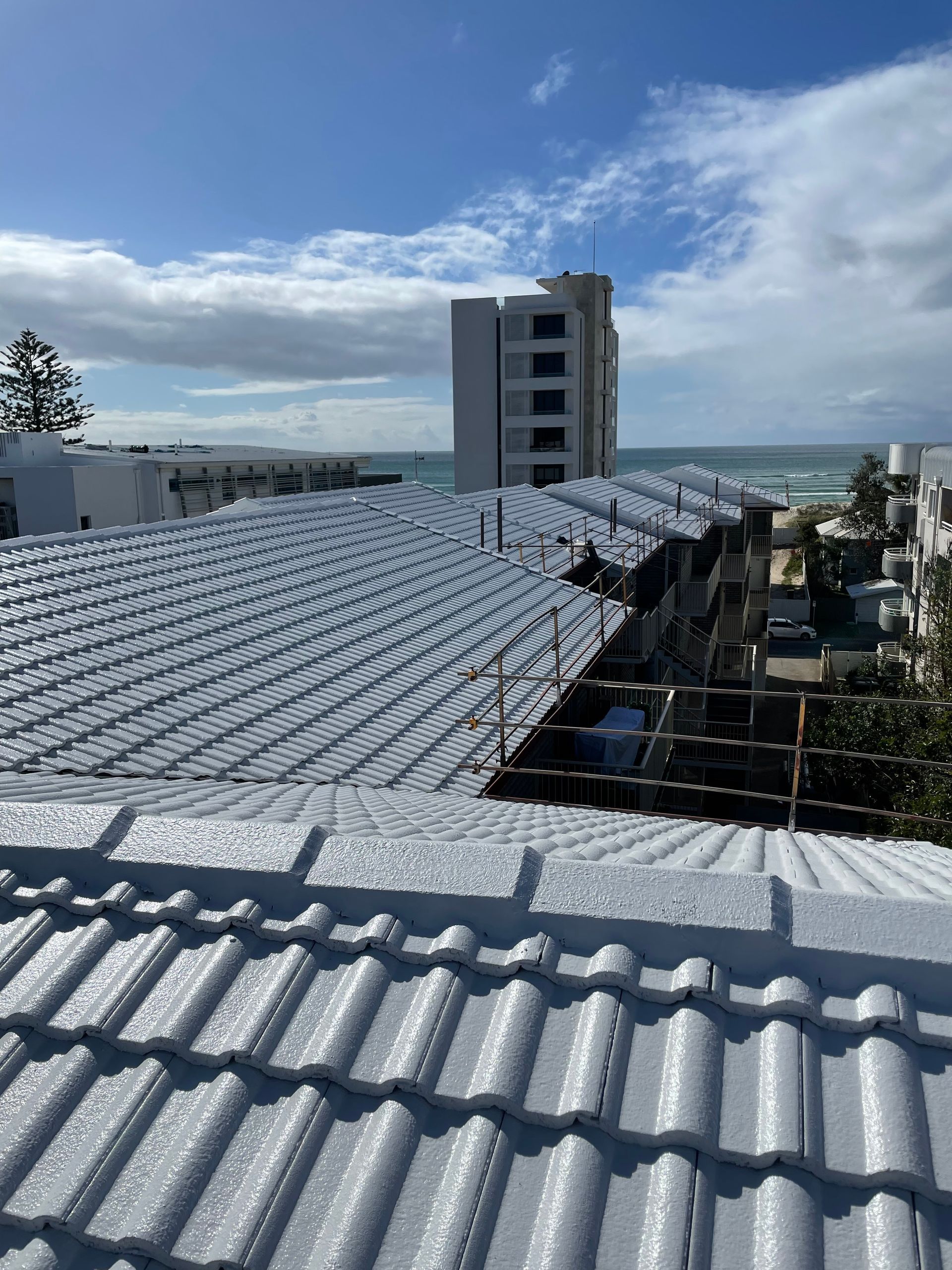 Worker on a roof with Electric drill Installing red metal tile on Wooden house
 — Roof Restoration in Southport QLD