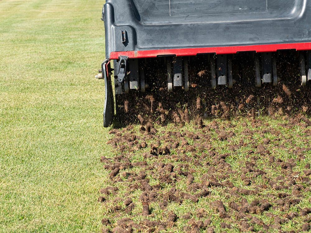 A person is using a machine to aerate a lawn.