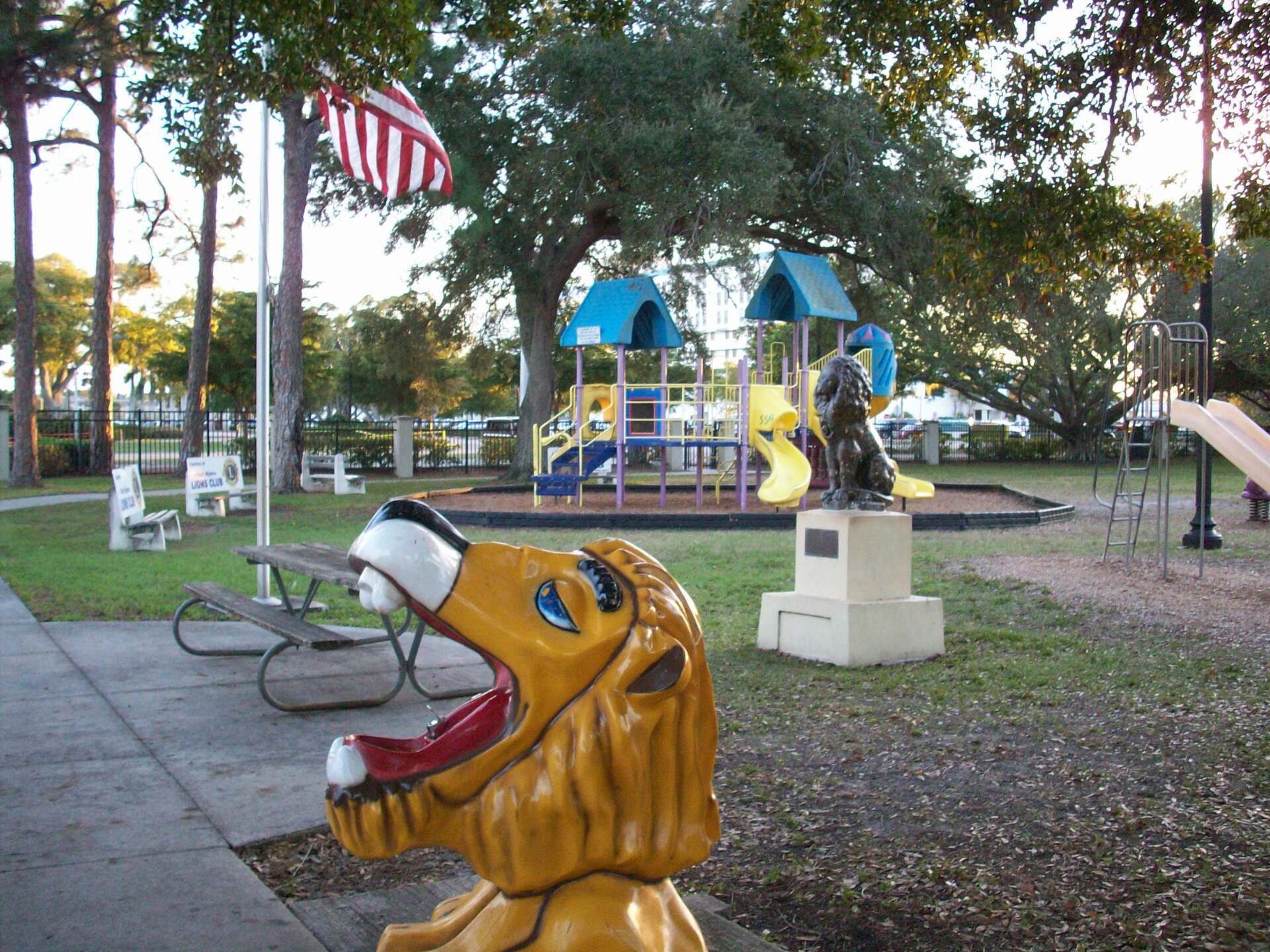 A statue of a lion with its mouth open in front of a playground