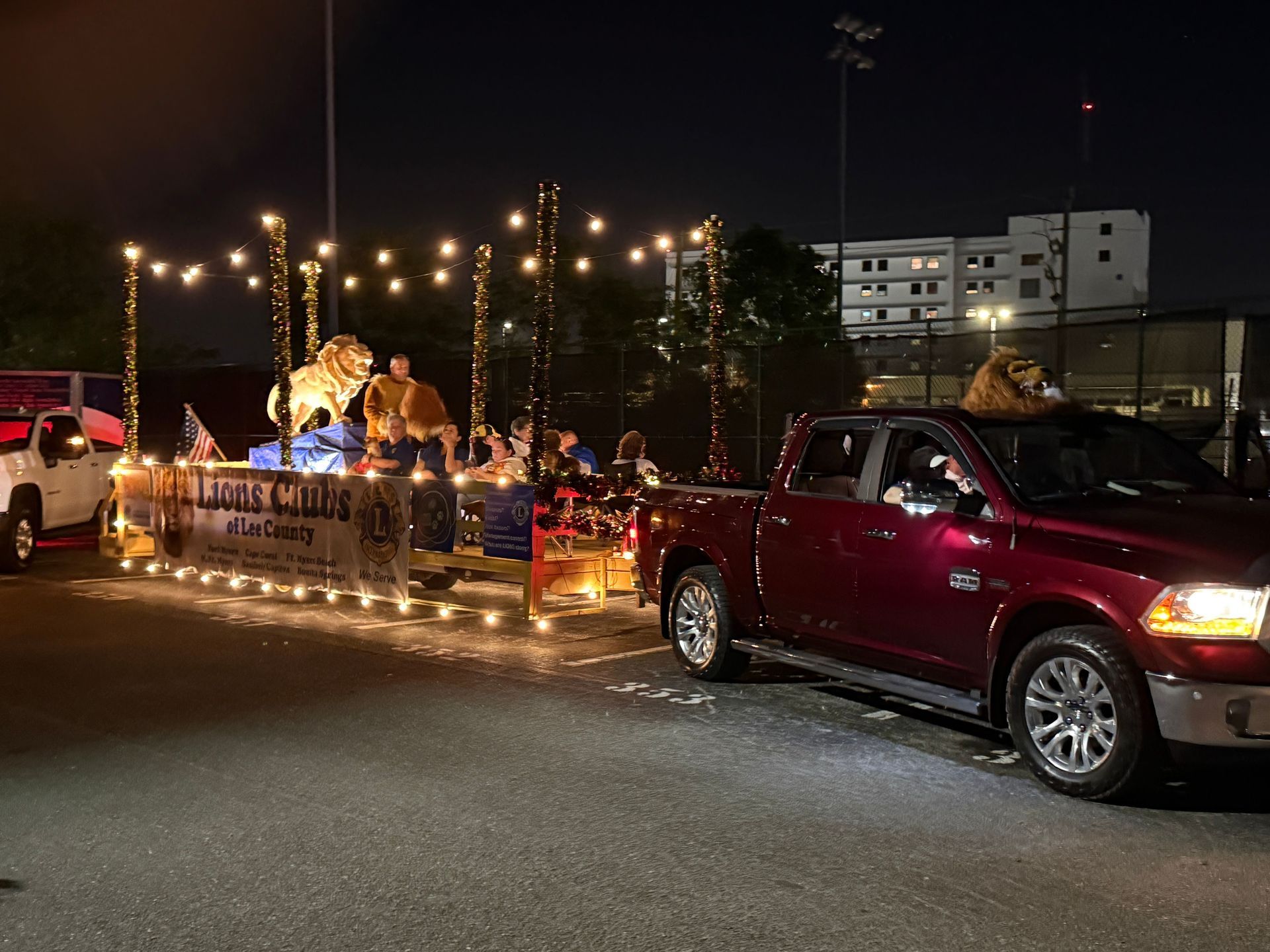 Parade float with lion decorations, pulled by a red truck, at night.