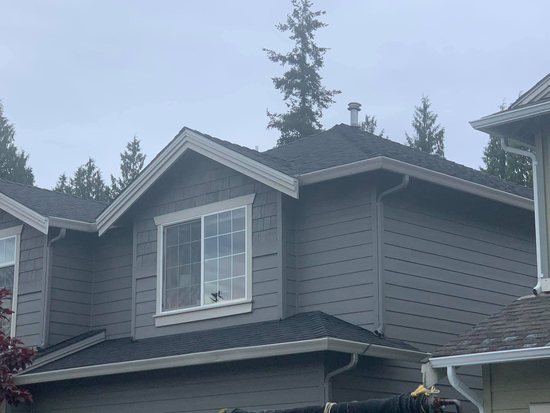 A gray house with a black roof and white windows