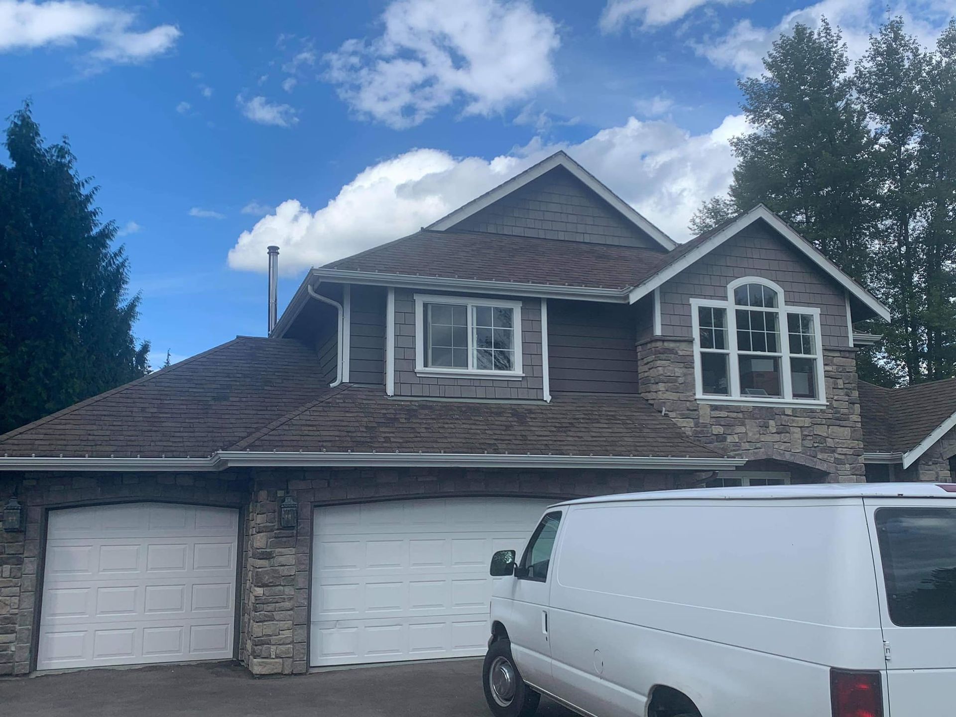 A white van is parked in front of a large house.