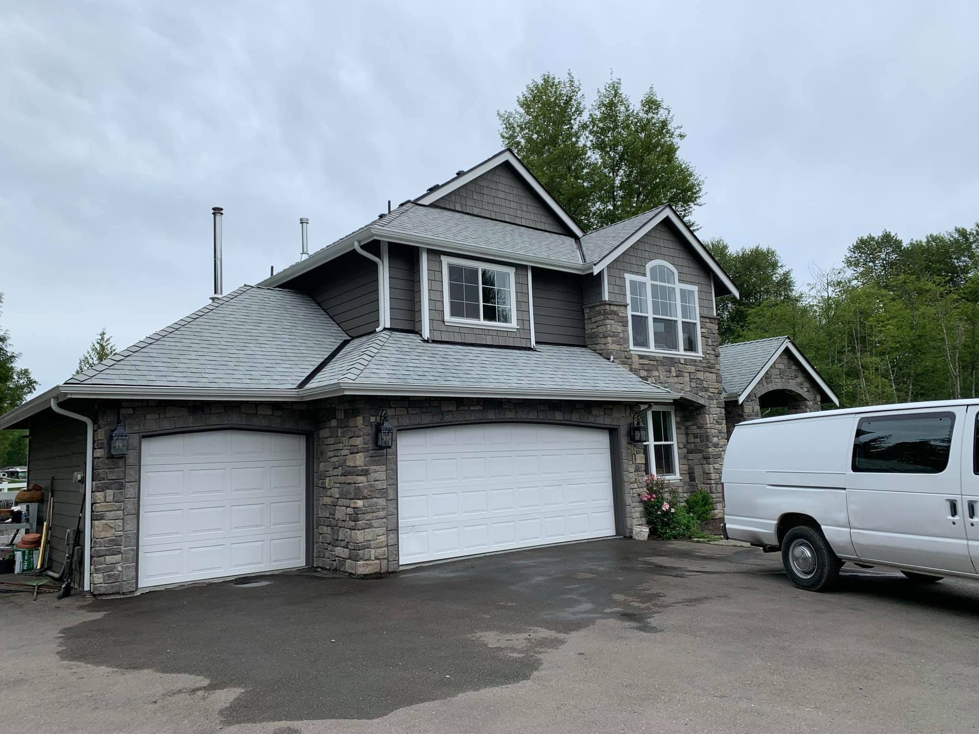A white van is parked in front of a large house.