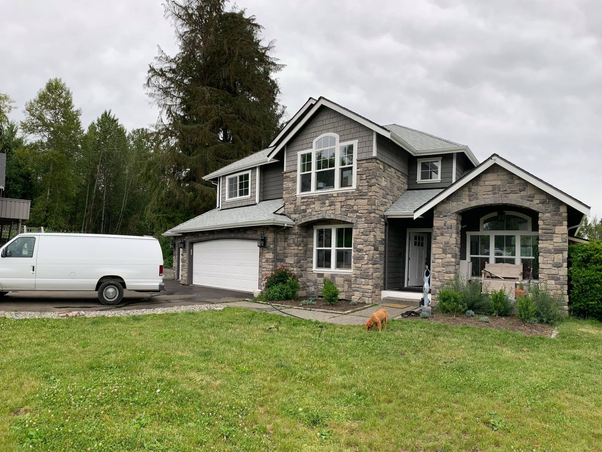 A white van is parked in front of a large house.