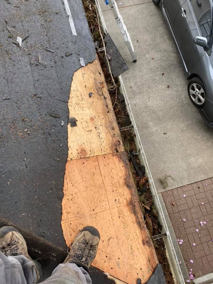 A person is standing on a roof next to a car.