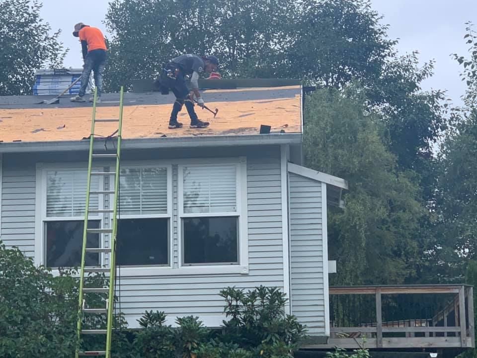 Two men are working on the roof of a house.
