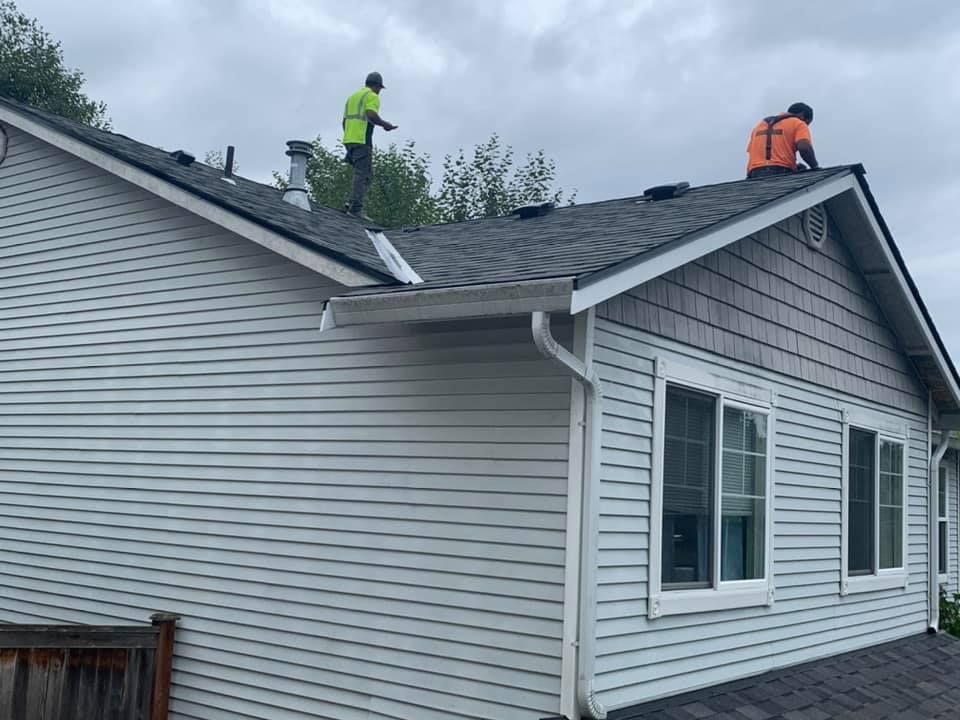 Two men are working on the roof of a house.