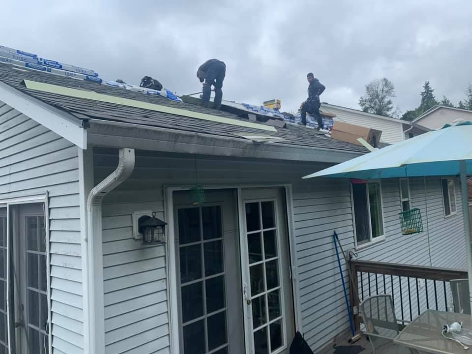 A group of men are working on the roof of a house.