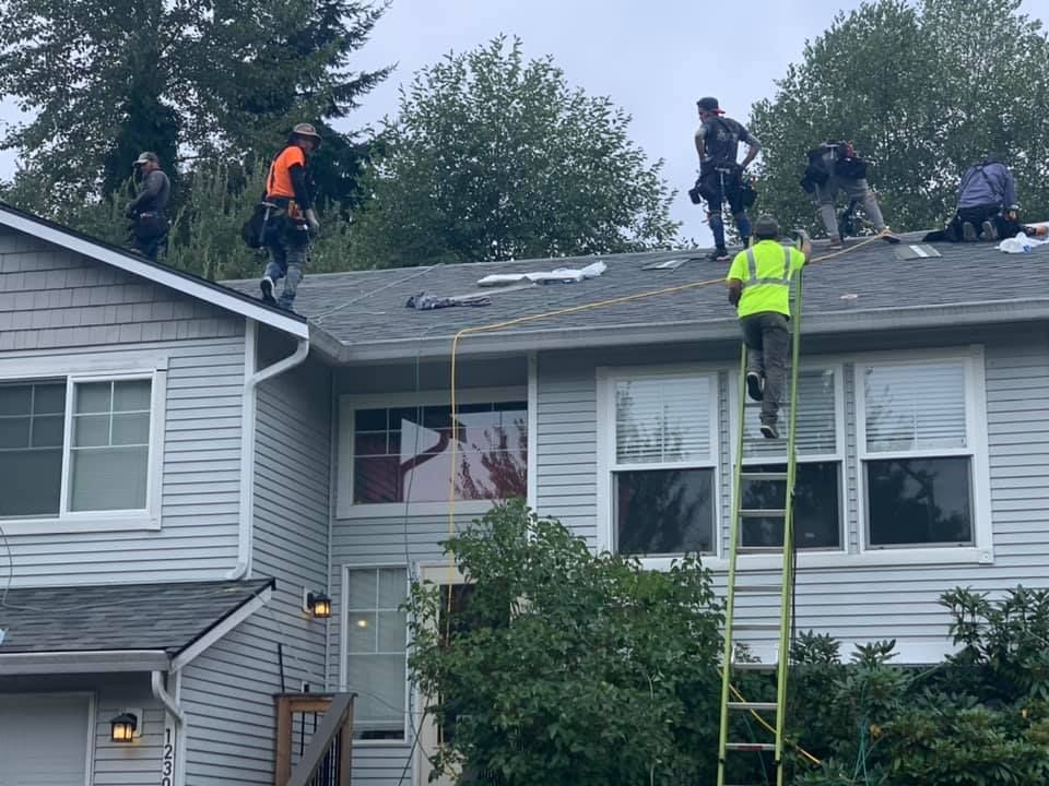 A group of men are working on the roof of a house.