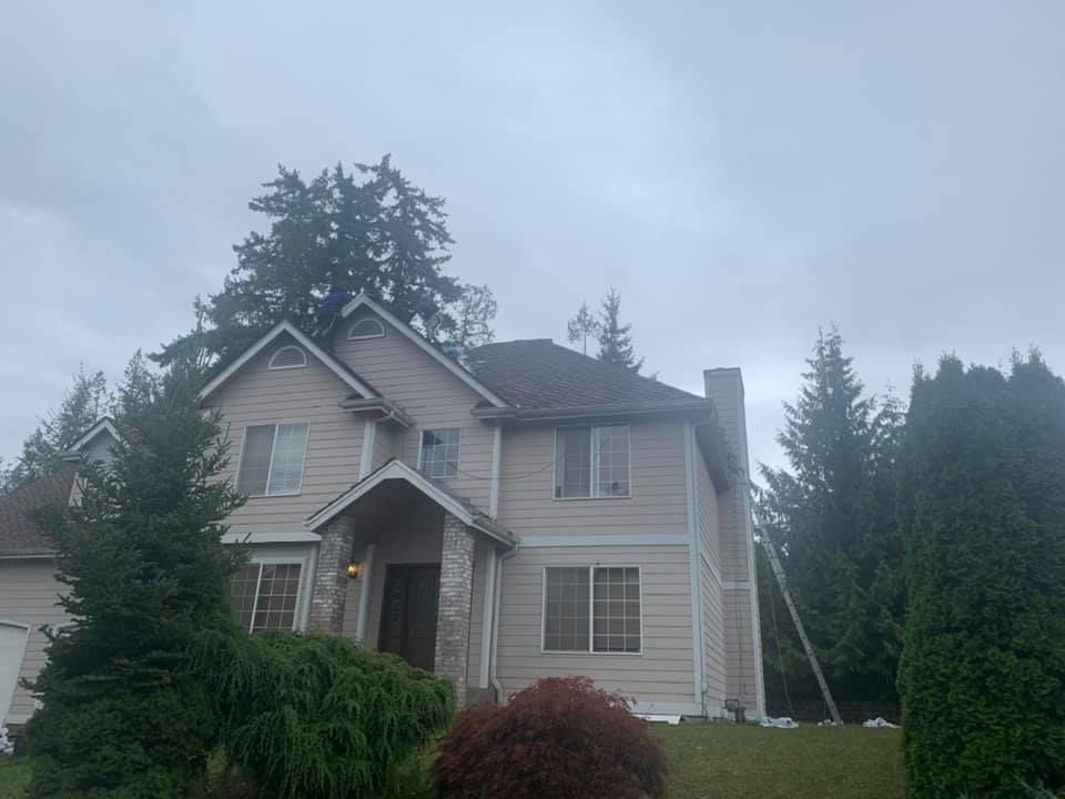 A large house with a lot of windows and trees in front of it on a cloudy day.