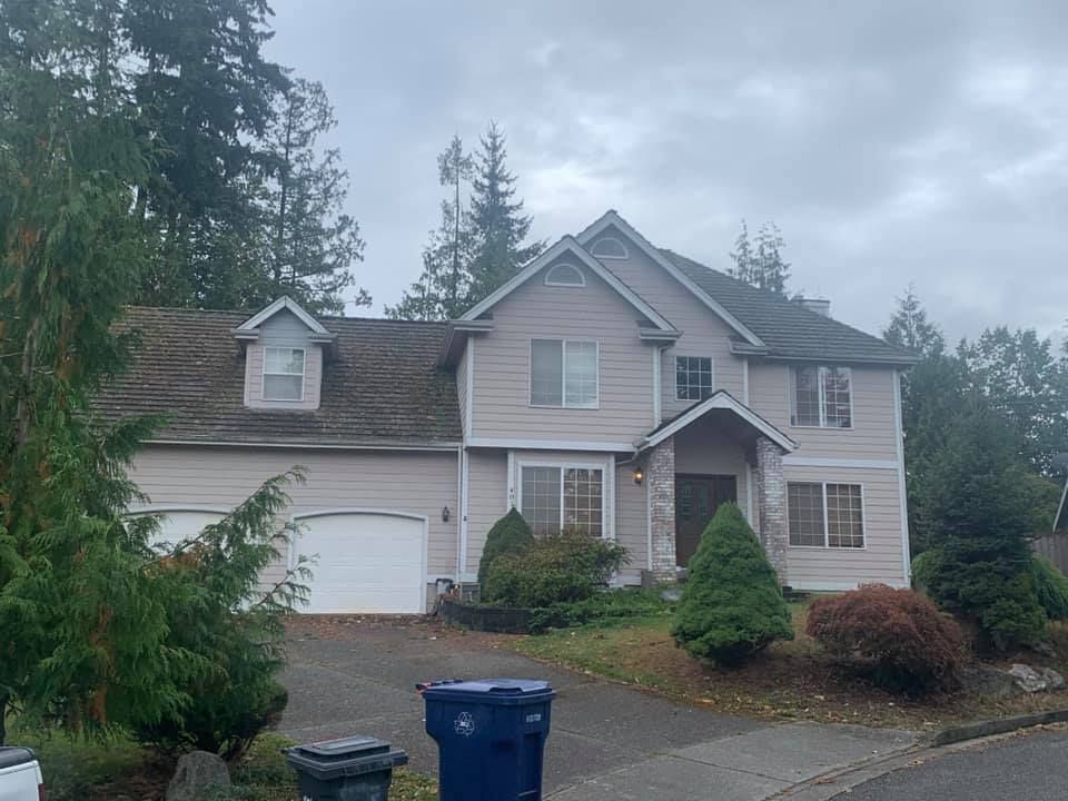 A large pink house with a blue trash can in front of it.