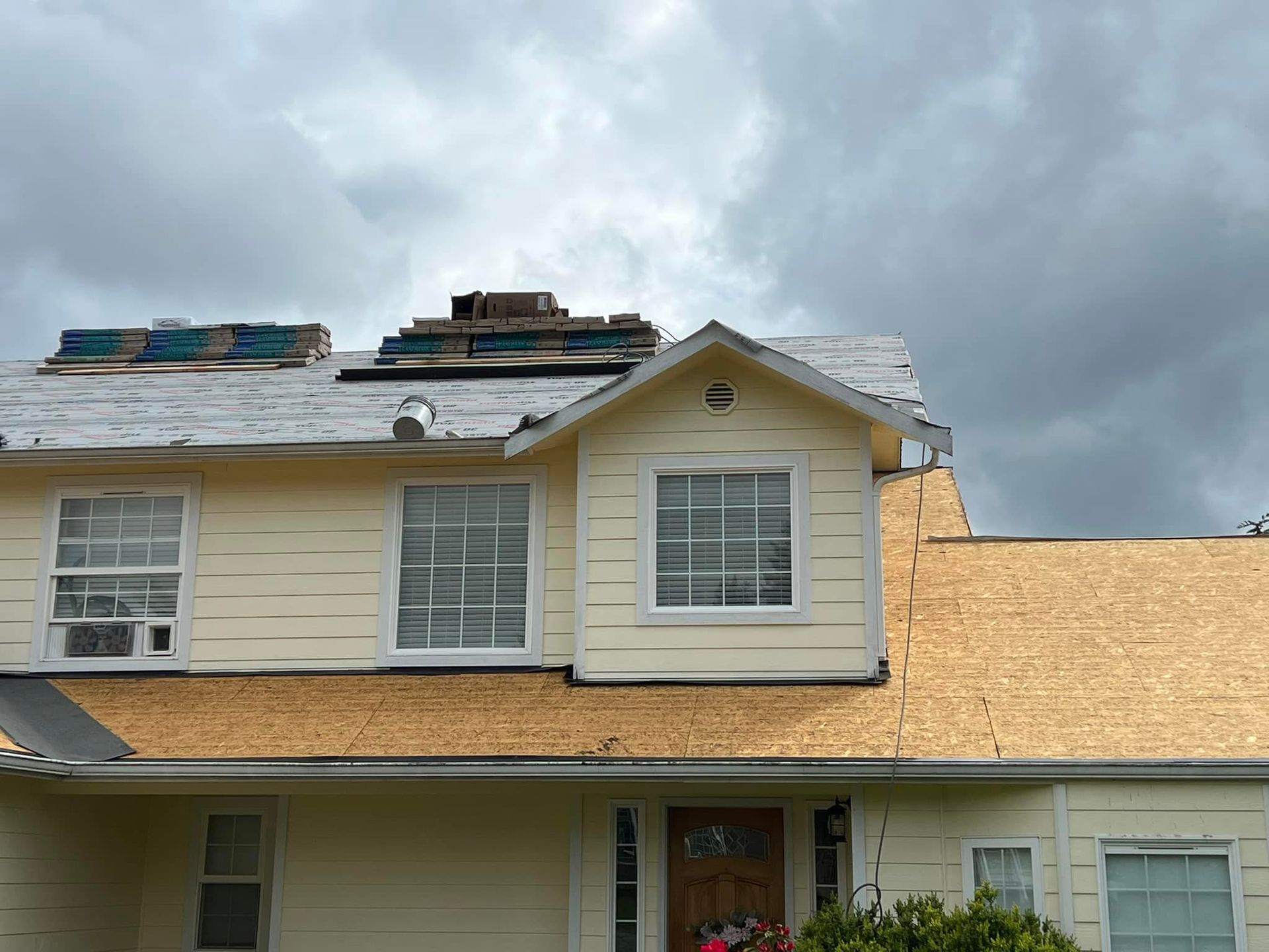 A house with a roof that is being installed on a cloudy day.